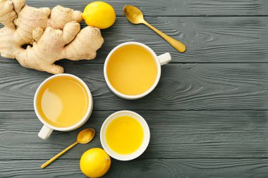 Koyu ahşap arka planda zencefilli, ballı ve limonlu çay fincanları