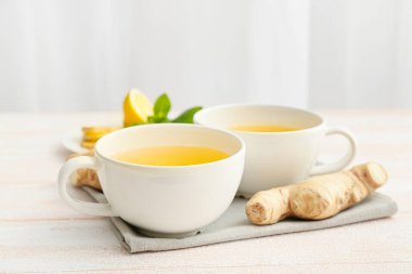 Hafif ahşap zemin üzerinde zencefilli, naneli ve limonlu çay fincanları