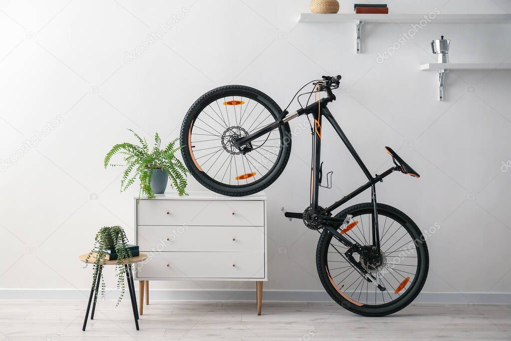 Modern bicycle and chest of drawers near white wall