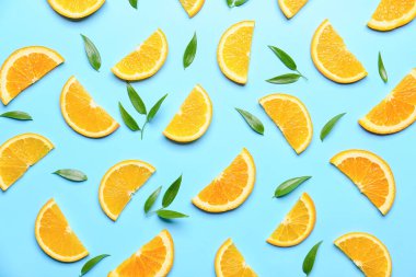 Arkaplanda yeşil yapraklı taze portakal dilimleri