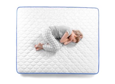 Beyaz arka planda yumuşak yatakta uyuyan olgun bir kadın.