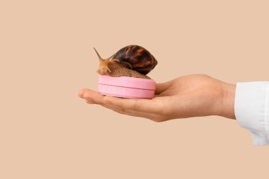 Kozmetik uzmanının elinde salyangoz ve sümüklü kozmetik var.