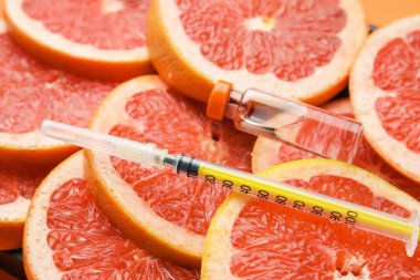 C vitamini ve greyfurt dilimlerine şırınga, yakın plan.