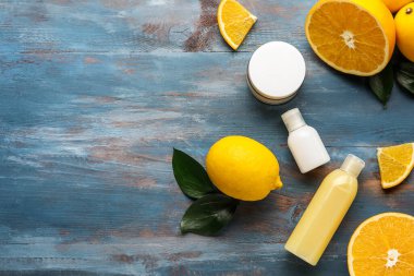 Renkli ahşap arka planda farklı kozmetik ürünleri ve narenciye meyveleri