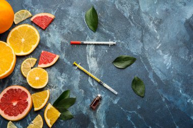 C vitamini, şırıngalar ve turunçgil meyveli ampule renk arkaplanı