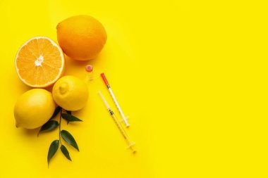 C vitamini, şırıngalar ve turunçgil meyveli ampule renk arkaplanı