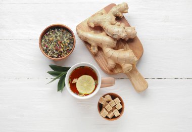 Lezzetli zencefilli çay ve hafif ahşap arka planda malzemelerle kompozisyon.