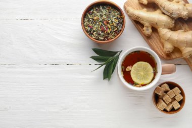 Lezzetli zencefilli çay ve hafif ahşap arka planda malzemelerle kompozisyon.