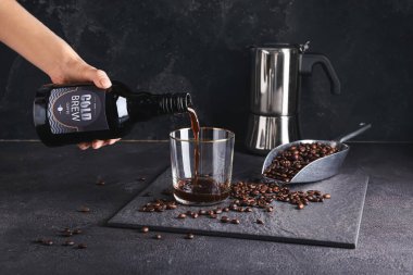 Kadın, arka planda şişeden cama lezzetli soğuk bira döküyor.