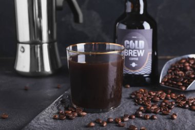 Lezzetli soğuk bira ve koyu arkaplanda kahve çekirdekleri olan kompozisyon