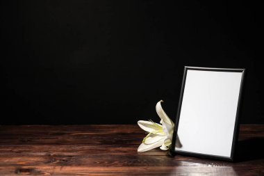 Üzerinde zambak çiçeği olan fotoğraf çerçevesi koyu arkaplanda