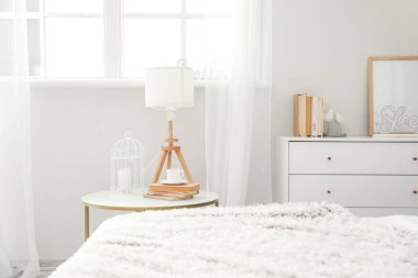 Modern odanın içinde lamba ve bir fincan kahveyle birlikte komodinin yanında.