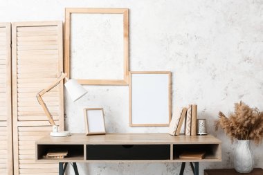 Lambalı, çerçeveli ve ışık duvarı yakınında kitapları olan modern işyeri