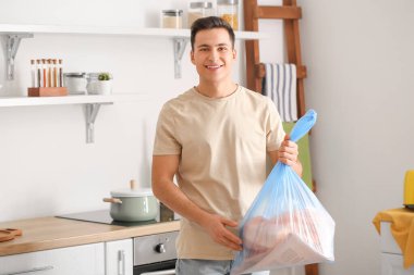 Evde çöp torbası olan bir adam var.