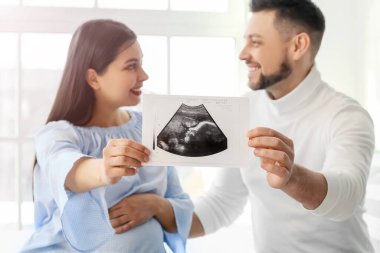Evde ultrason görüntüsü olan güzel hamile bir çift.