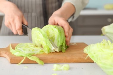 Mutfaktaki masada marul kesen kadın, yakın plan.
