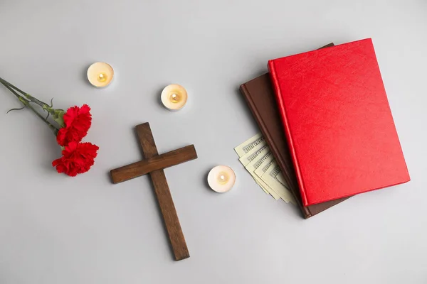 光の背景に本 お金とカーネーションの花と木製の十字架 — ストック写真