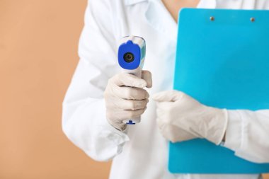 Renk arkaplanı üzerinde kızılötesi termometresi olan doktor, kapat