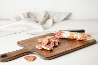 Açık arkaplanda salam dilimleri olan tahta