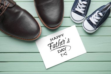 Babalar günü için renkli ahşap arka planda tebrik kartı olan büyük ve küçük ayakkabılar.