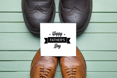 Babalar günü için renkli ahşap arka planda tebrik kartı olan büyük ve küçük ayakkabılar.