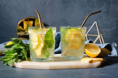 Koyu arkaplanda zencefilli limonata bardakları olan tahta.