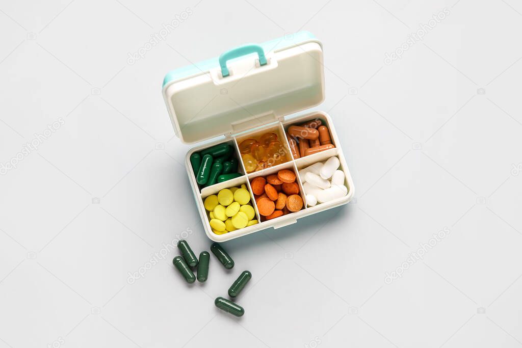 Container with different pills on white background