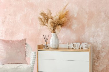 Renkli duvarın yanında dekoru ve koltuğu olan şık çekmeceler.