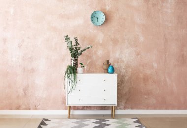 Renk duvarının yanında dekoru ve çiçekleri olan şık çekmeceler.