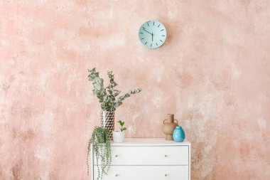 Renk duvarının yanında dekoru ve çiçekleri olan şık çekmeceler.
