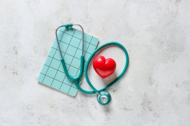 Işık arka planında kalp ve defter olan modern steteskop