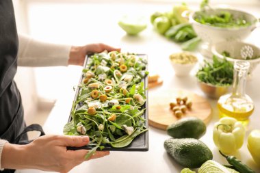 Mutfakta lezzetli salatalı kadın tabağı tutuyor.