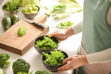 Elinde taze salata kaseleri olan bir kadın.