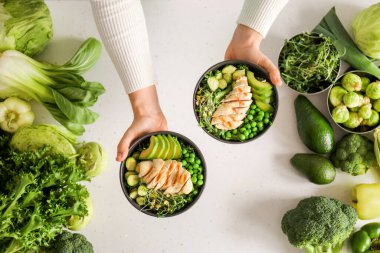 Kadın eli ve tabaklar dolusu lezzetli salata ve hafif arka planda taze sebzeler.