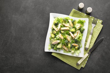 Koyu arkaplanda taze sebzeli bir tabak lezzetli salata.