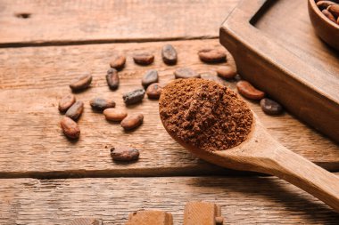 Tahta zemin üzerinde kakao tozu olan kaşık.