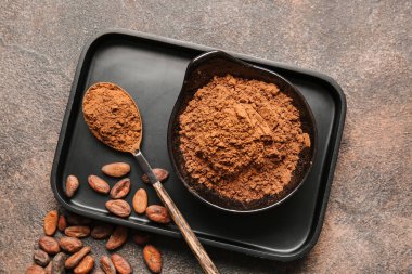 Arkaplanda kakao tozu olan kase ve kaşık.