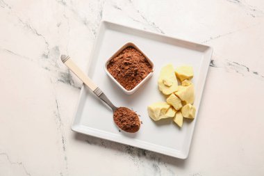 Hafif arka planda kakao tozu ve tereyağlı kase ve kaşık