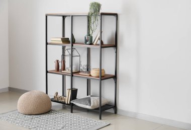 Beyaz duvarın yanında kitapları ve dekorasyonu olan modern raf ünitesi.