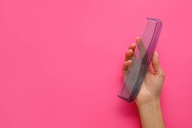 Arkaplanda plastik saç tarağı olan bir kadın el.