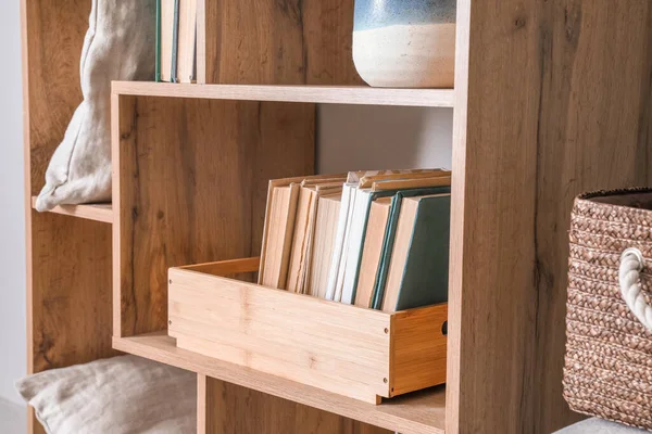 Wooden shelf with books and decor, closeup