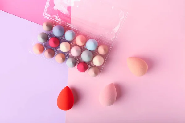 色の背景に化粧スポンジ付きのプラスチック製の卵ホルダー — ストック写真