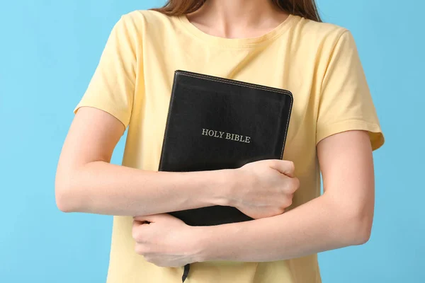 Young woman with Bible on color background, closeup