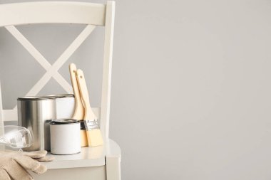 Işık duvarının yanındaki boya ve aletlerle dolu sandalye.