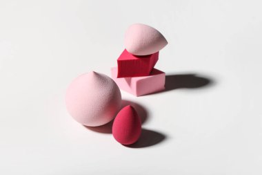 Beyaz arkaplanda farklı makyaj süngerleri, yakın plan