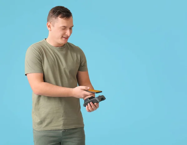 Junger Mann Mit Zahlungsterminal Und Handy Auf Farbigem Hintergrund — Stockfoto