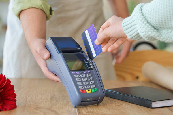 Buyer paying for order in flower shop via terminal, closeup