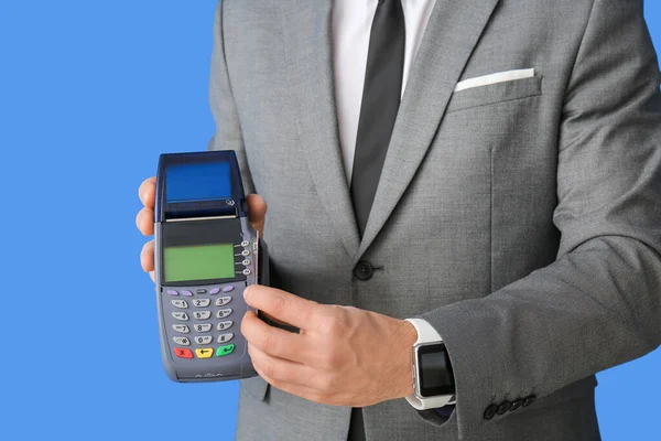 Businessman with payment terminal on color background, closeup