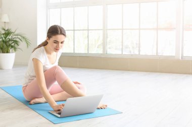 Kilitleme sırasında laptoplu genç bir kadın evde yoga yapıyor.
