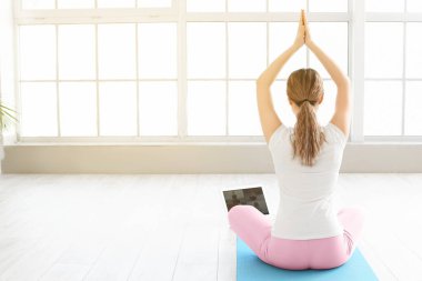 Kilitleme sırasında laptoplu genç bir kadın evde yoga yapıyor.
